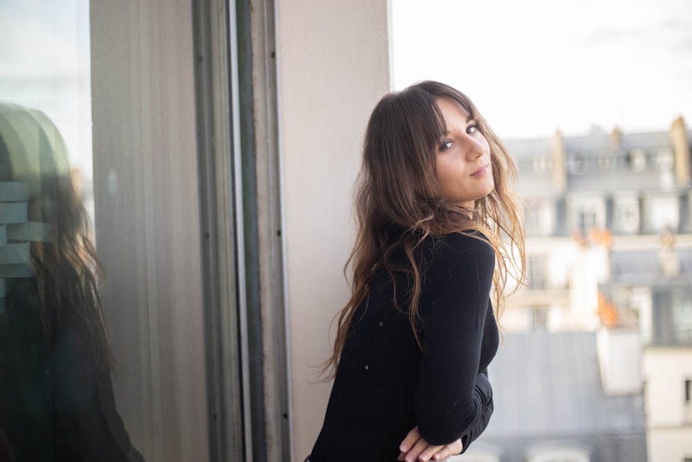 woman in black long sleeve shirt standing beside glass window