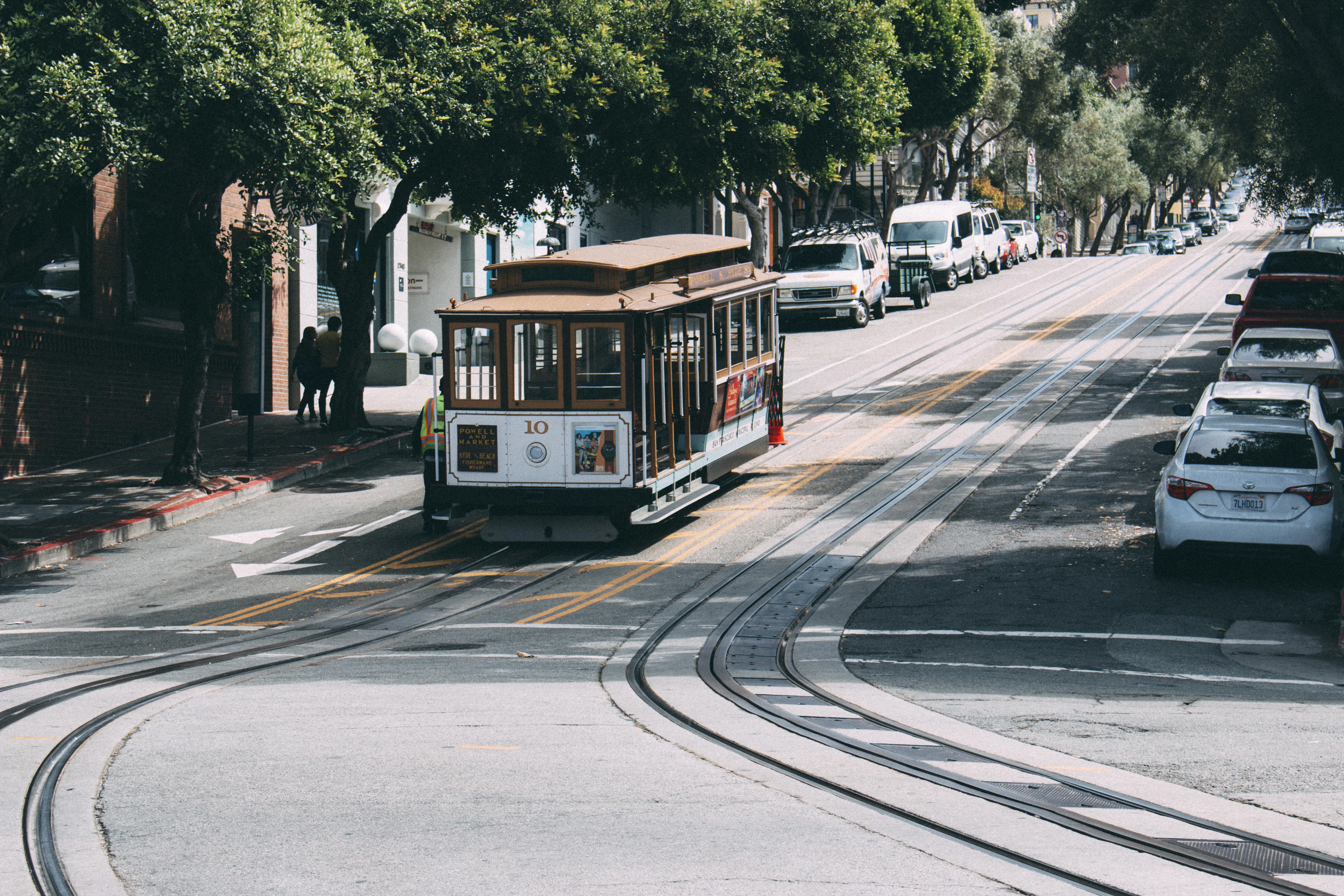A cable car climbing a tree-lined street in San Francisco