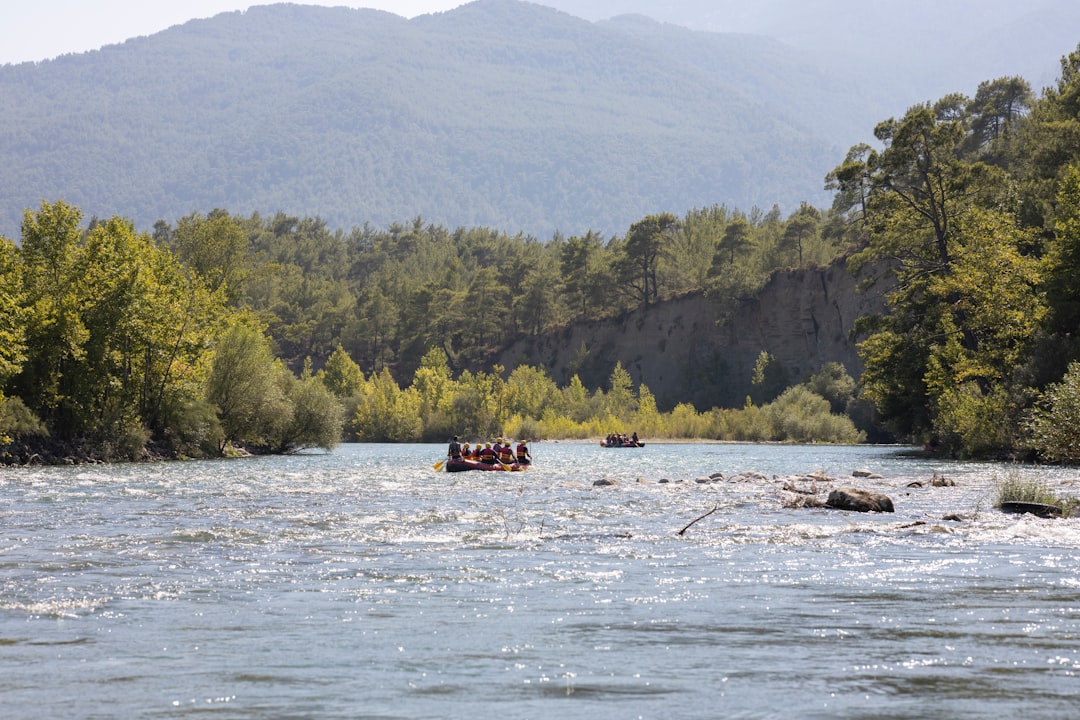 red boat on body of water near green mountain during daytime