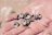 Close-up of a hand applying creamy lotion next to aqua and tan seashells on a sandy surface