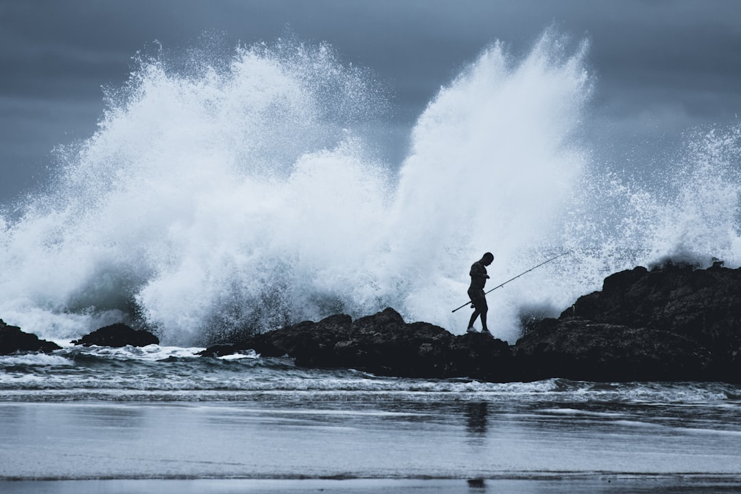 man standing on rock near sea waves during daytime