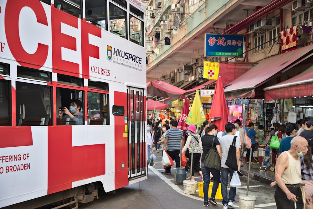 people walking on street near red tram during daytime