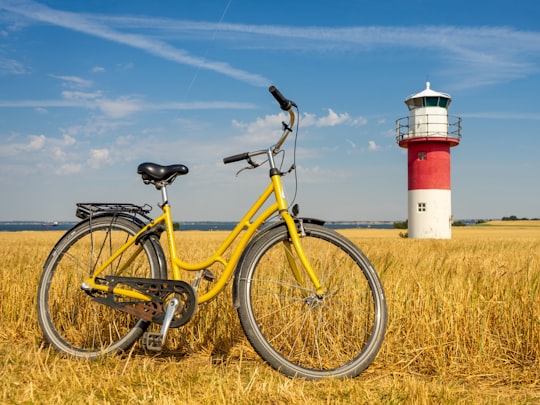 yellow bicycle near red and white lighthouse under blue sky during daytime in Hven Sweden