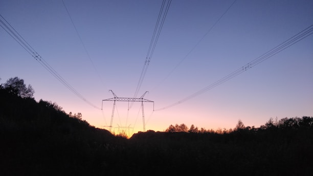 High-voltage outdoor power cables laid out on a construction site under a sunset sky.