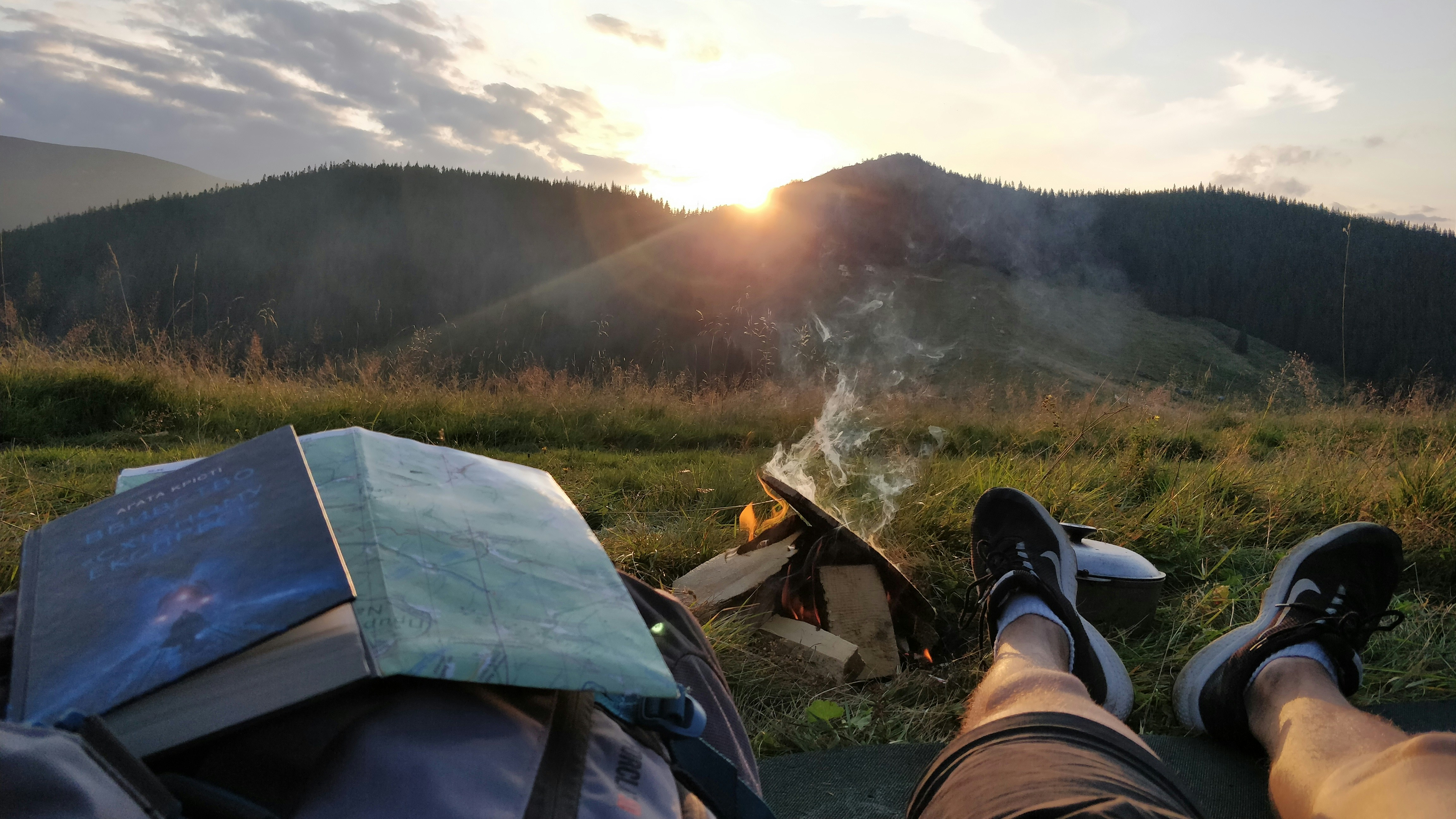 person in black hiking shoes sitting on green grass field during daytime