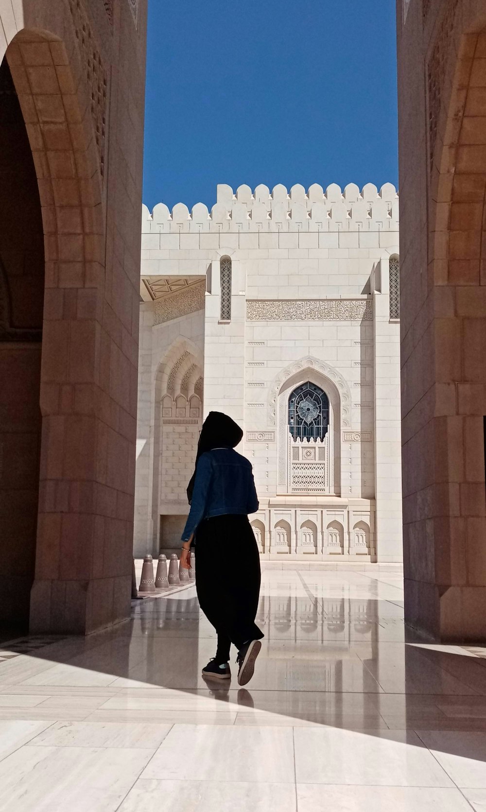 woman in blue hijab standing in front of brown concrete building