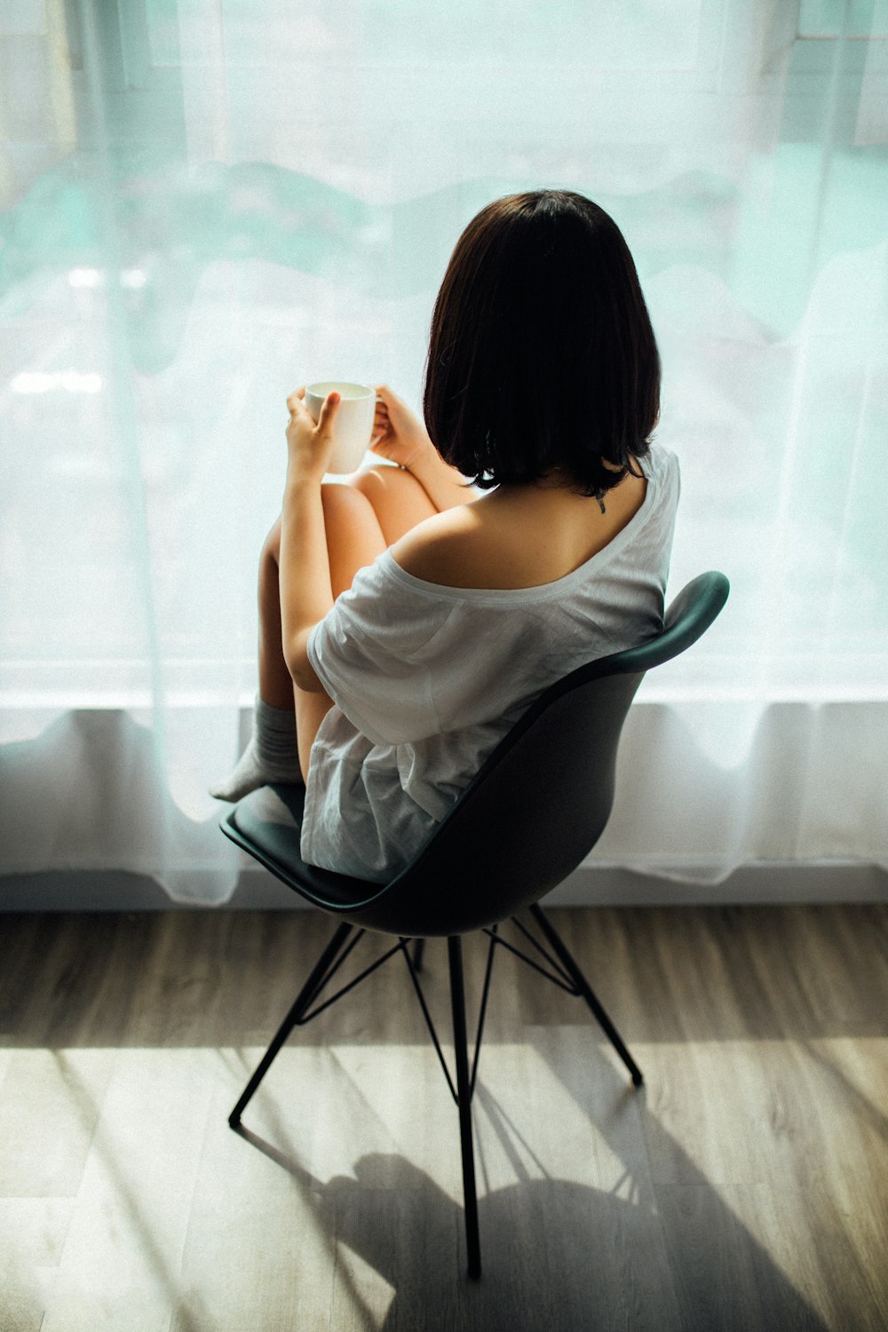 femme en débardeur blanc assise sur une chaise