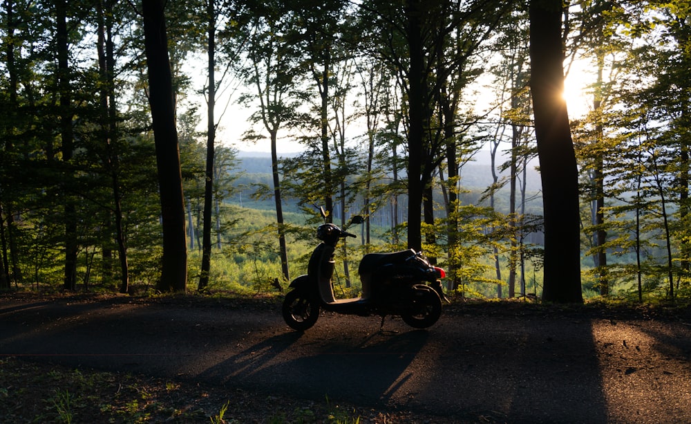 black motorcycle parked on road near trees during daytime