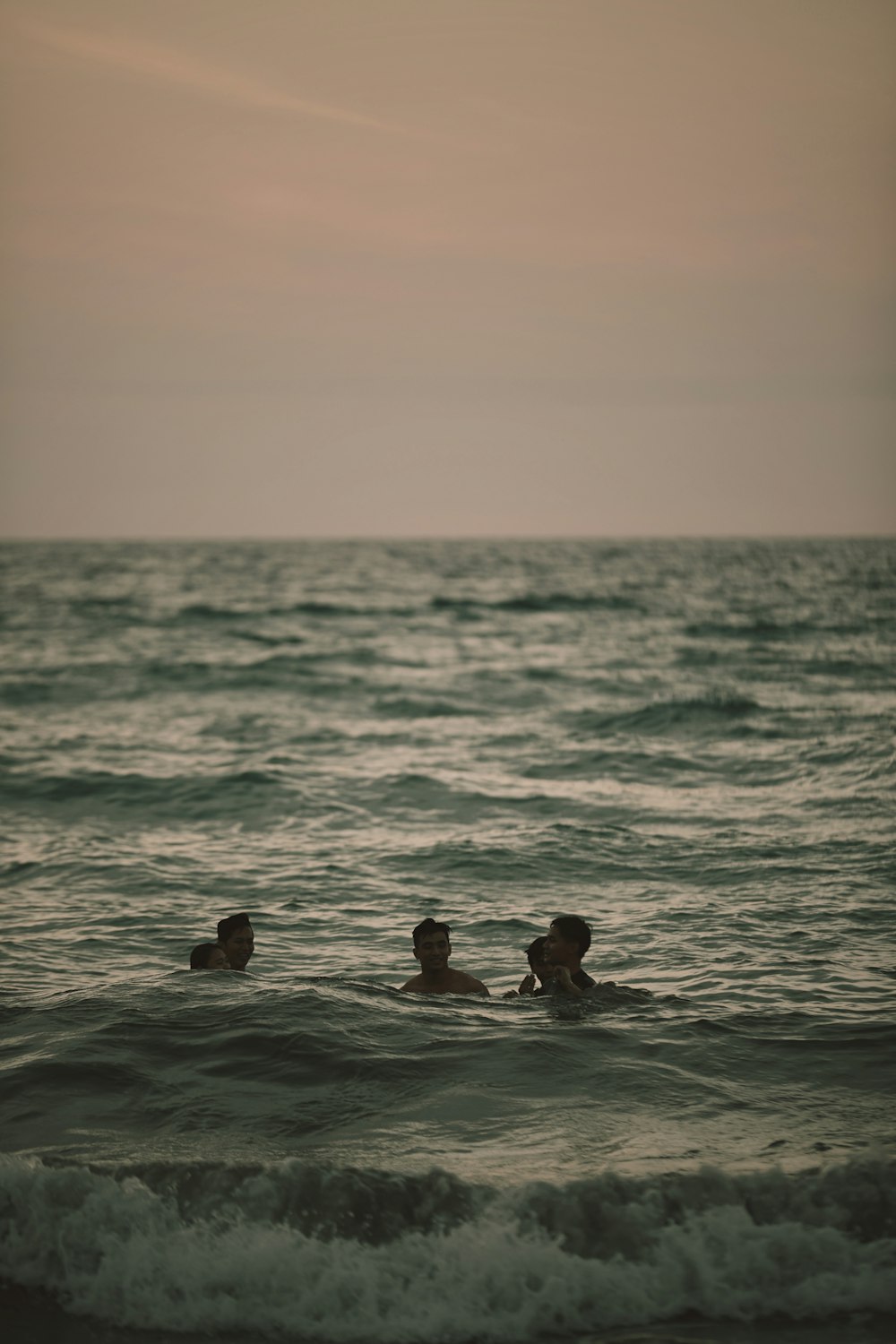 3 people swimming on sea during daytime