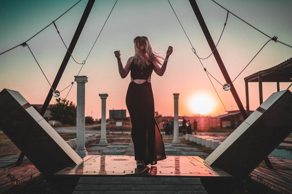 woman in black tank top and black pants standing on brown wooden dock during daytime