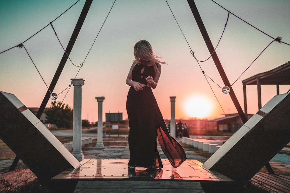 woman in black long sleeve dress standing on brown wooden dock during daytime