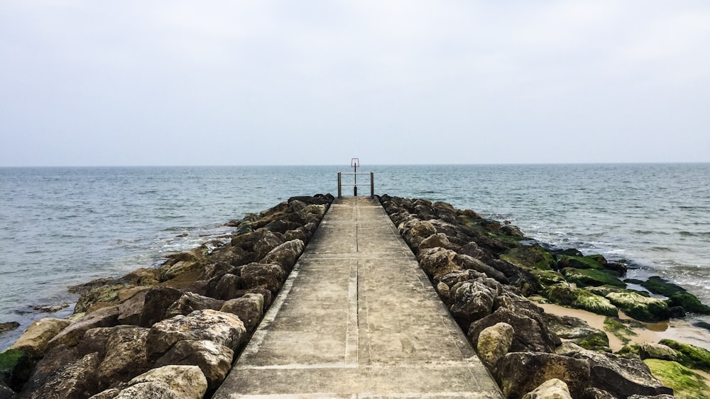 a long concrete pier stretching out into the ocean