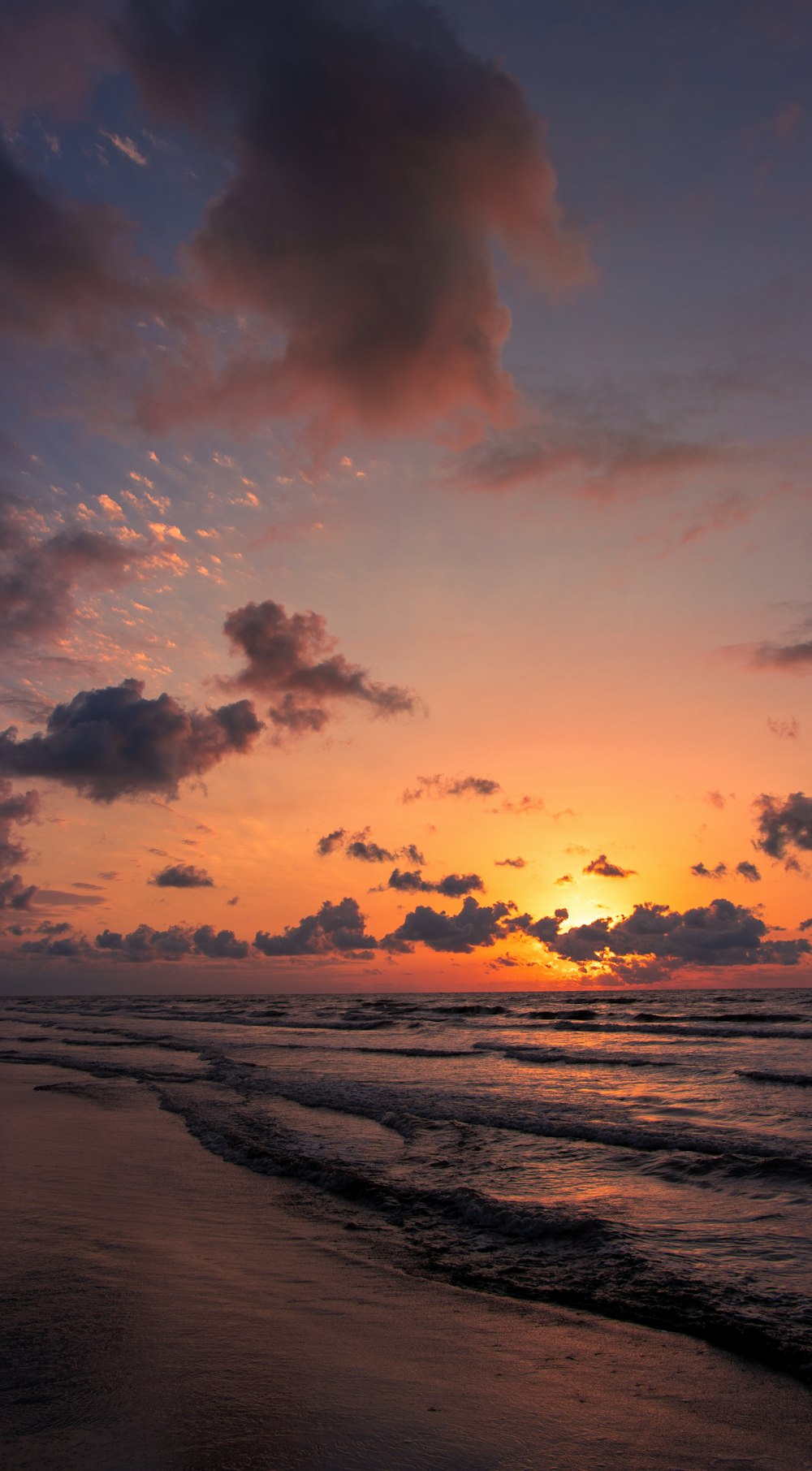 the sun is setting over the ocean on the beach