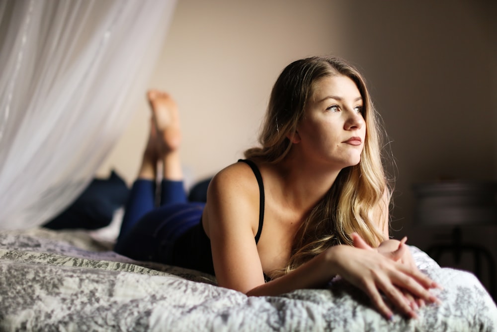 woman in black spaghetti strap top lying on bed