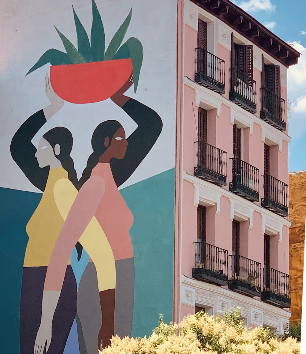 mujer con camiseta sin mangas negra y pantalones azules de pie junto a la pared blanca con rojo y azul