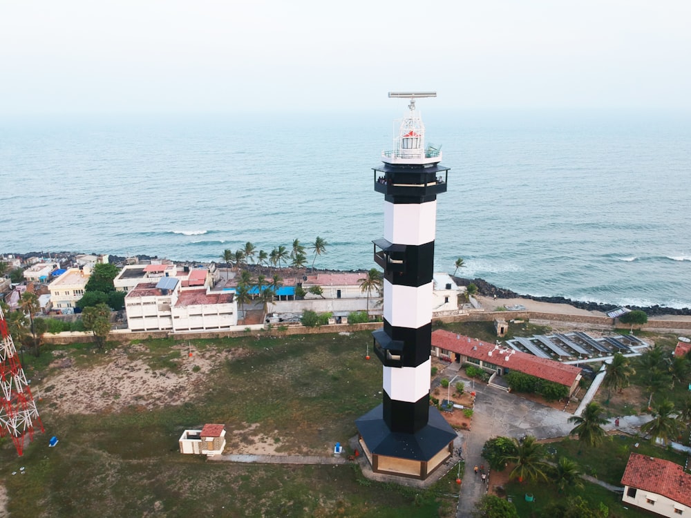 Phare blanc et noir près d’un plan d’eau pendant la journée