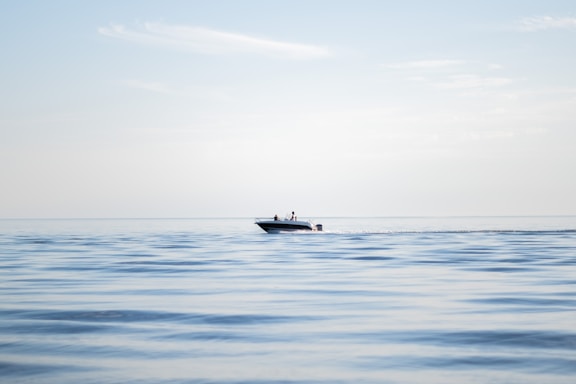 A sleek speedboat cutting through sparkling blue water under a clear sky.