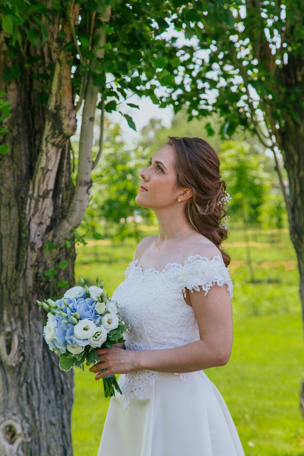 woman in white floral dress holding blue flowers