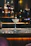 A dimly lit cocktail glass garnished with a vibrant twist of citrus on a sleek black marble bar.