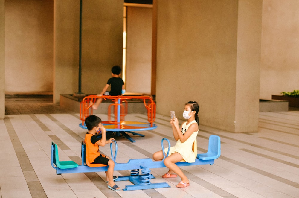 2 boys sitting on blue and red basketball court