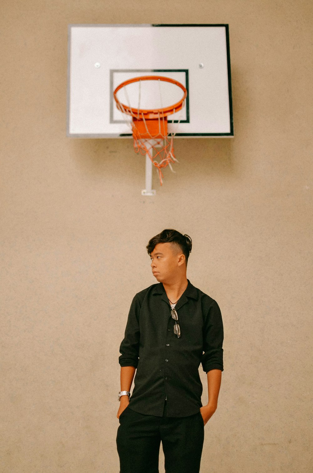 man in black polo shirt standing beside basketball hoop