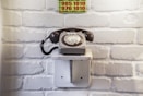 contactez-nous  par téléphone ici - an old fashioned telephone on a wall in front of a brick wall