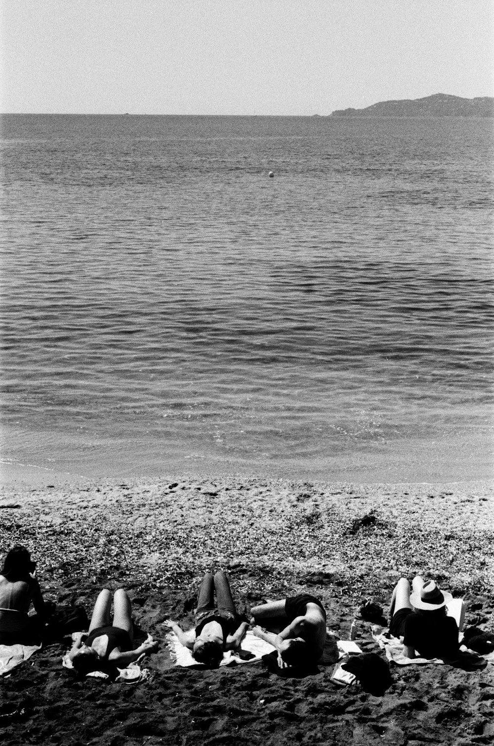 grayscale photo of people sitting on beach shore