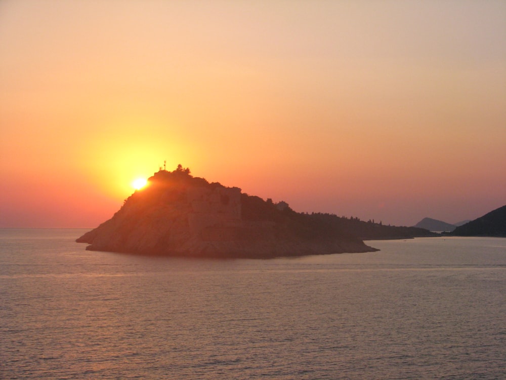 silhouette of mountain near body of water during sunset