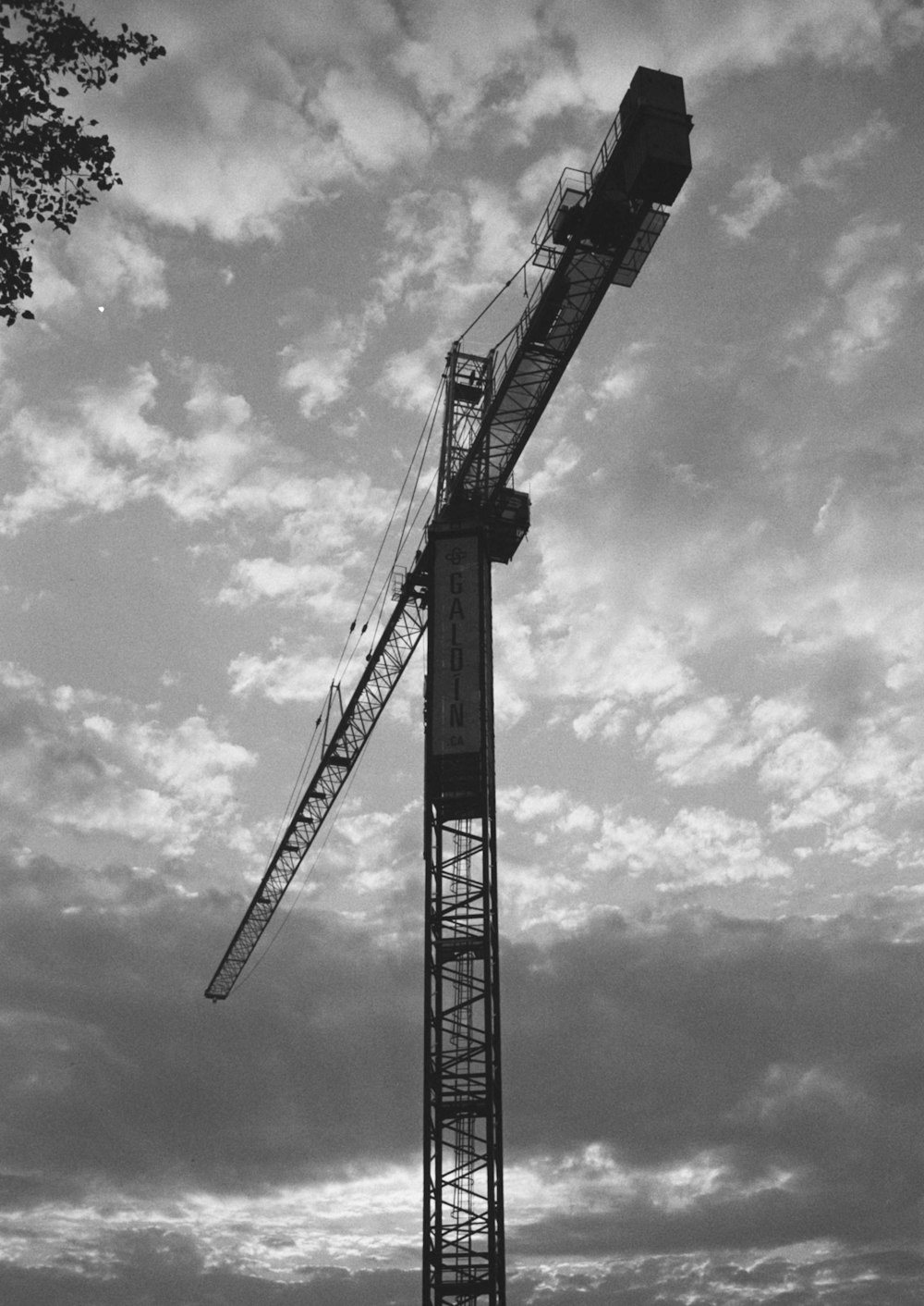 grayscale photo of crane under cloudy sky