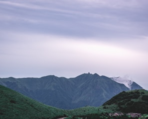 A scenic view of a green plot of land with hills in the background in Raigad.