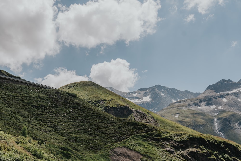 green grass covered mountain under white clouds and blue sky during daytime