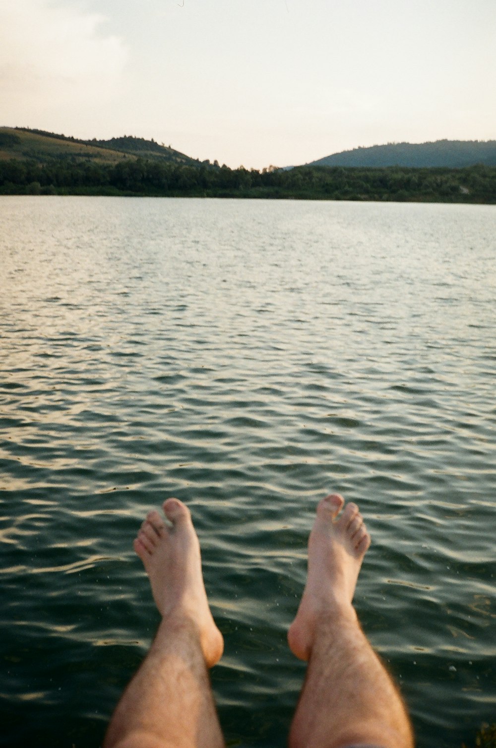 persons feet on body of water during daytime