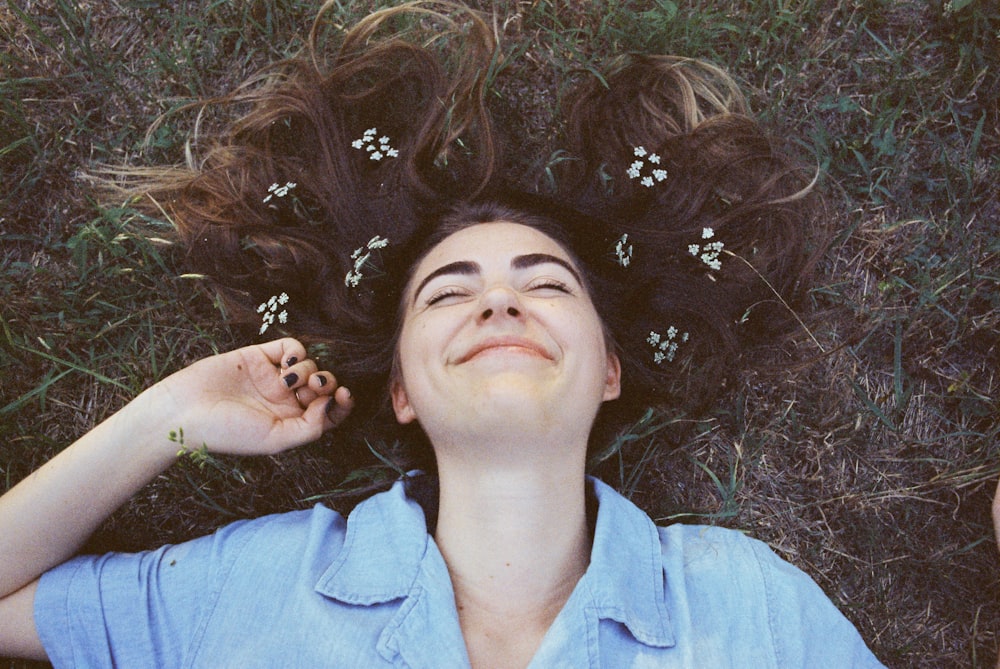 woman in blue button up shirt lying on grass