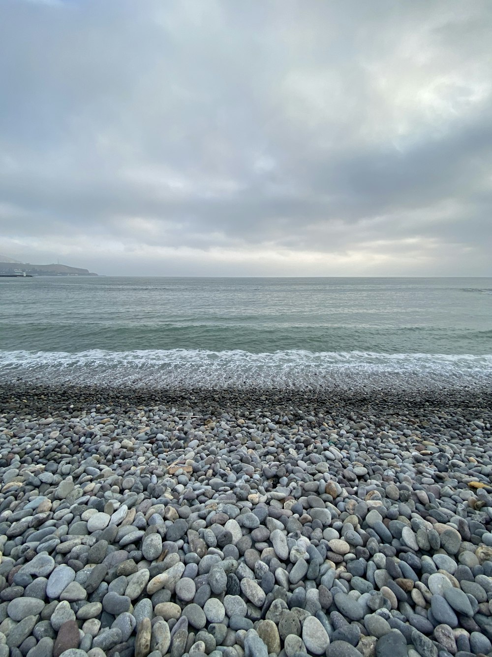 gray and white pebbles on seashore under cloudy sky during daytime