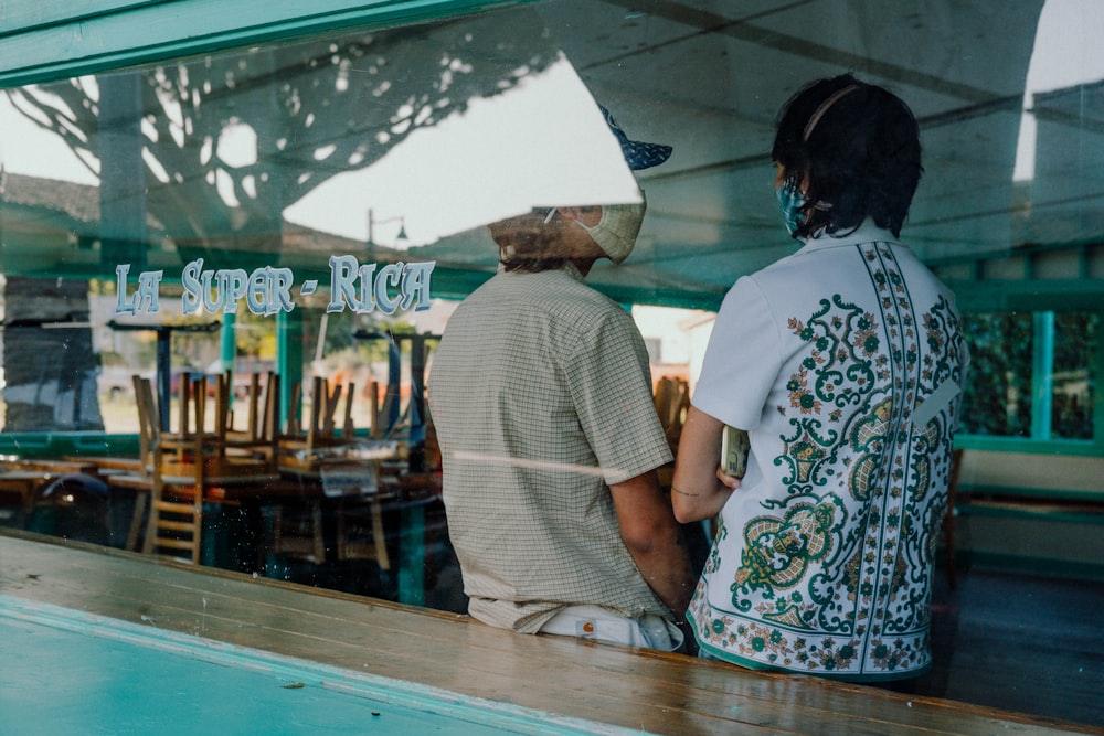 man in white t-shirt standing beside woman in blue and white floral dress