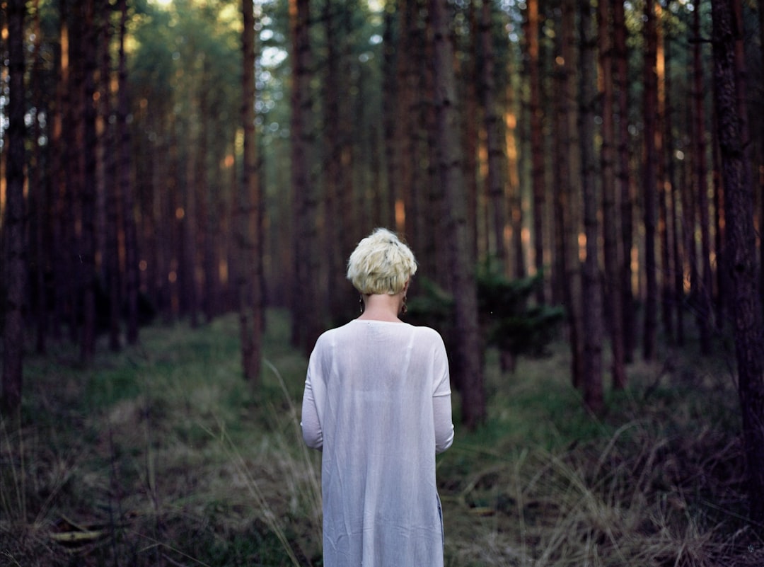 man in white dress shirt standing in forest during daytime