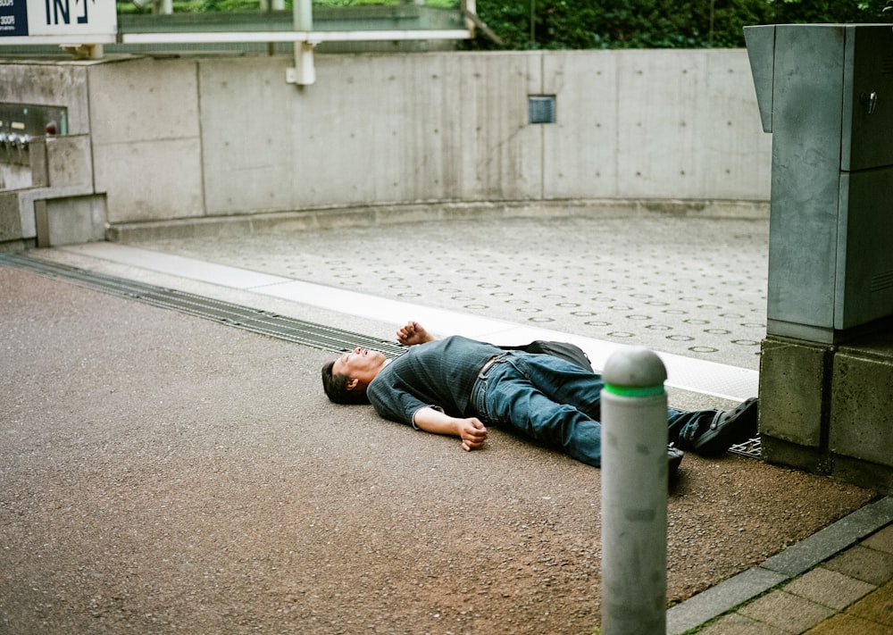 Homme en T-shirt noir allongé sur un sol en béton gris