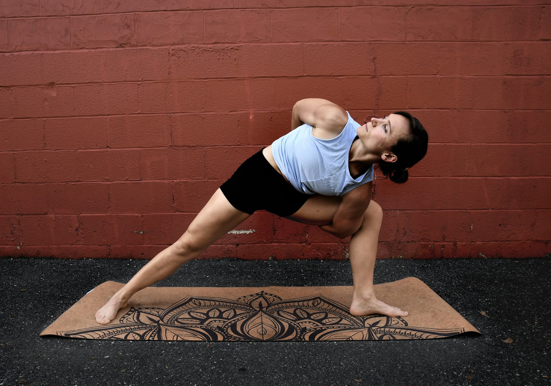 Woman on a cork mat in a deep side lunge with her arms wrapped behind her in a bind