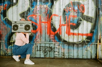 A vibrant graffiti-covered brick wall with a glowing neon boombox and cassette tapes scattered around.