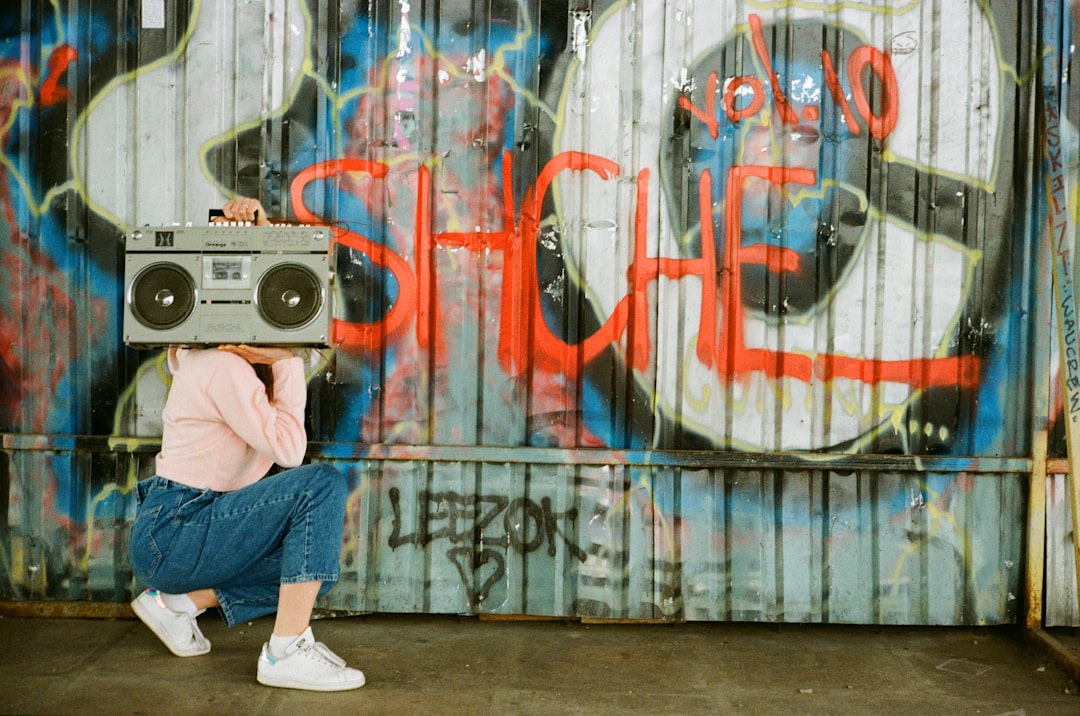 man in blue denim jeans and white sneakers standing in front of graffiti wall