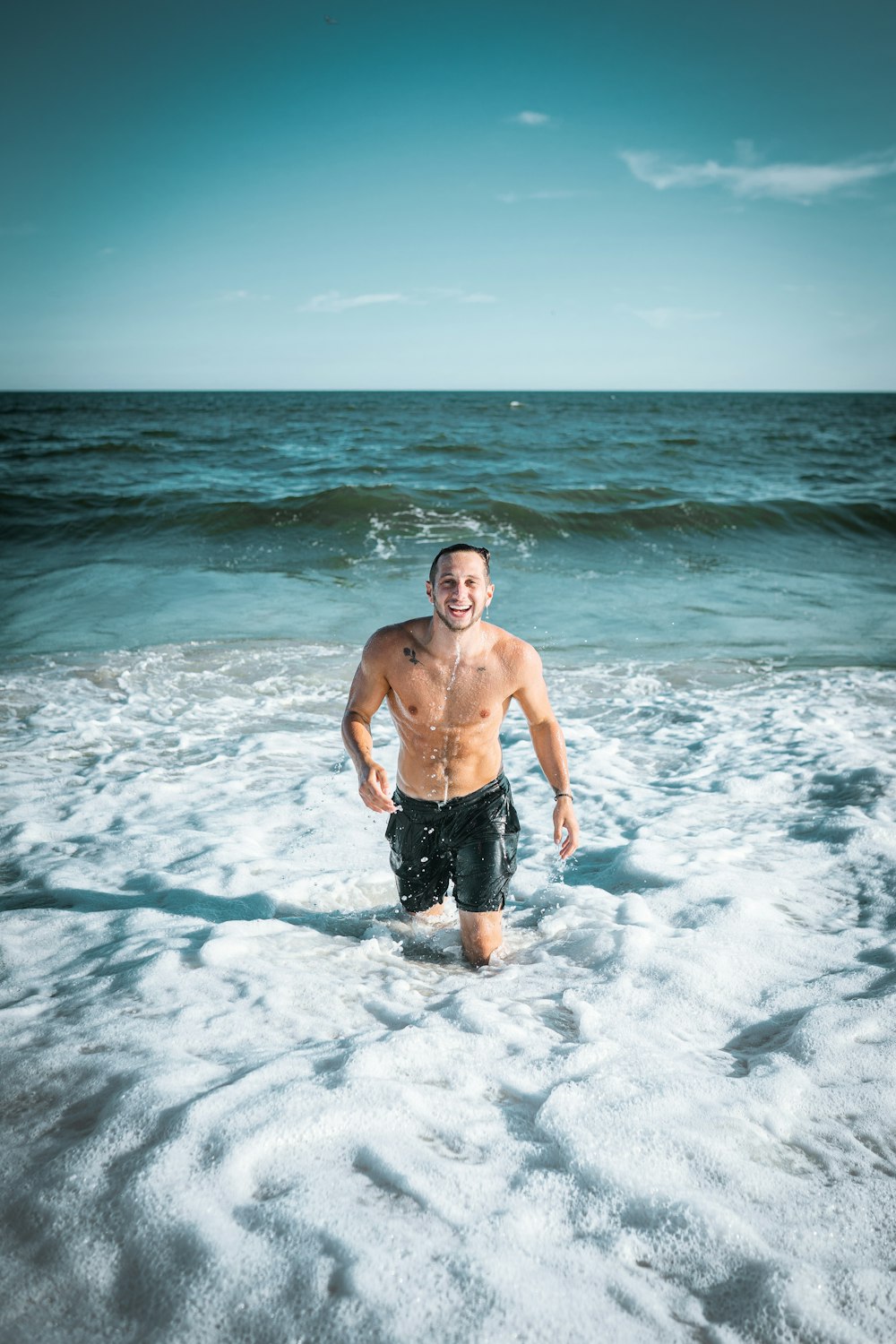 man in black shorts standing on sea water during daytime