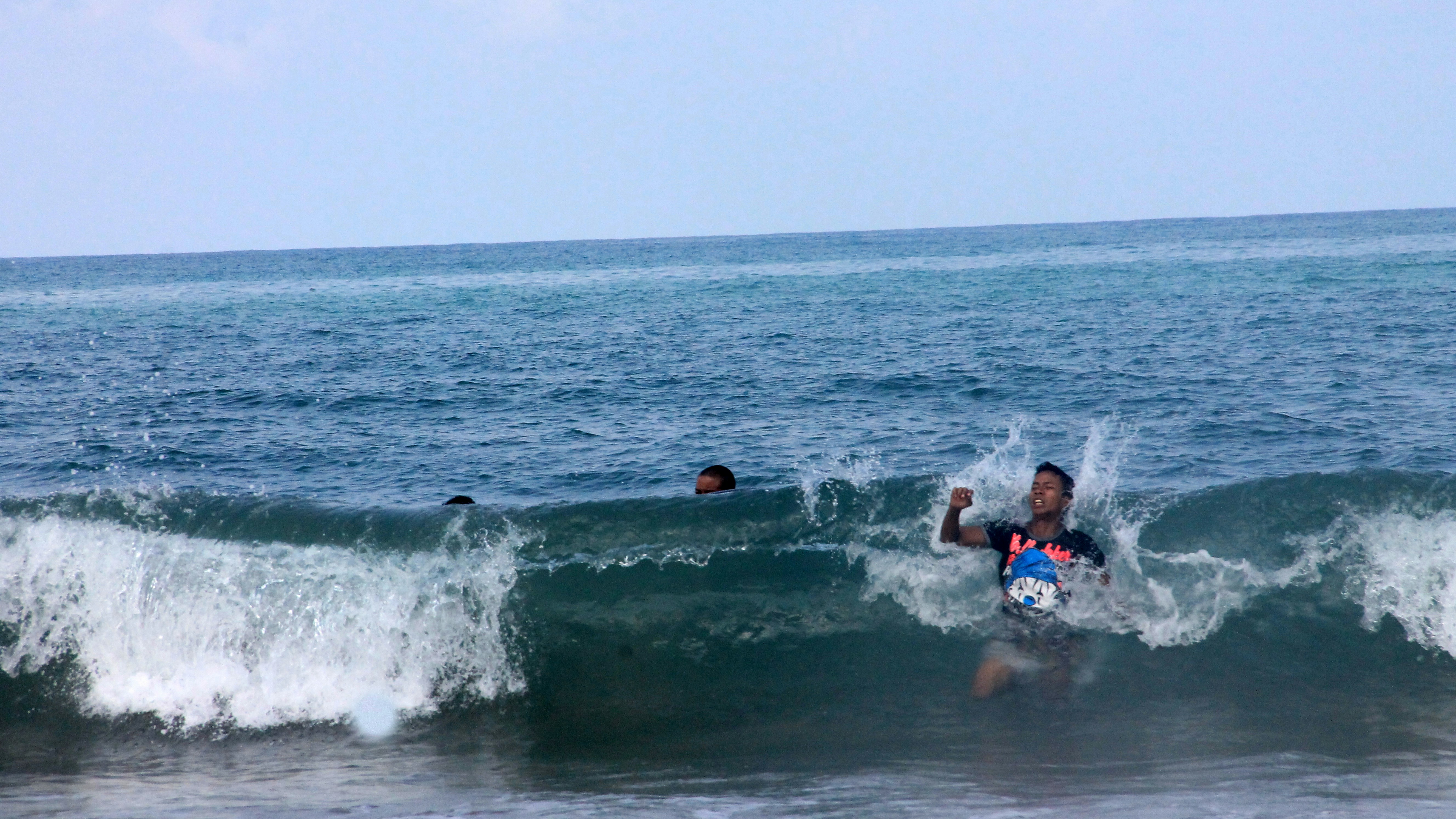 2 men in blue and red shorts swimming on sea during daytime