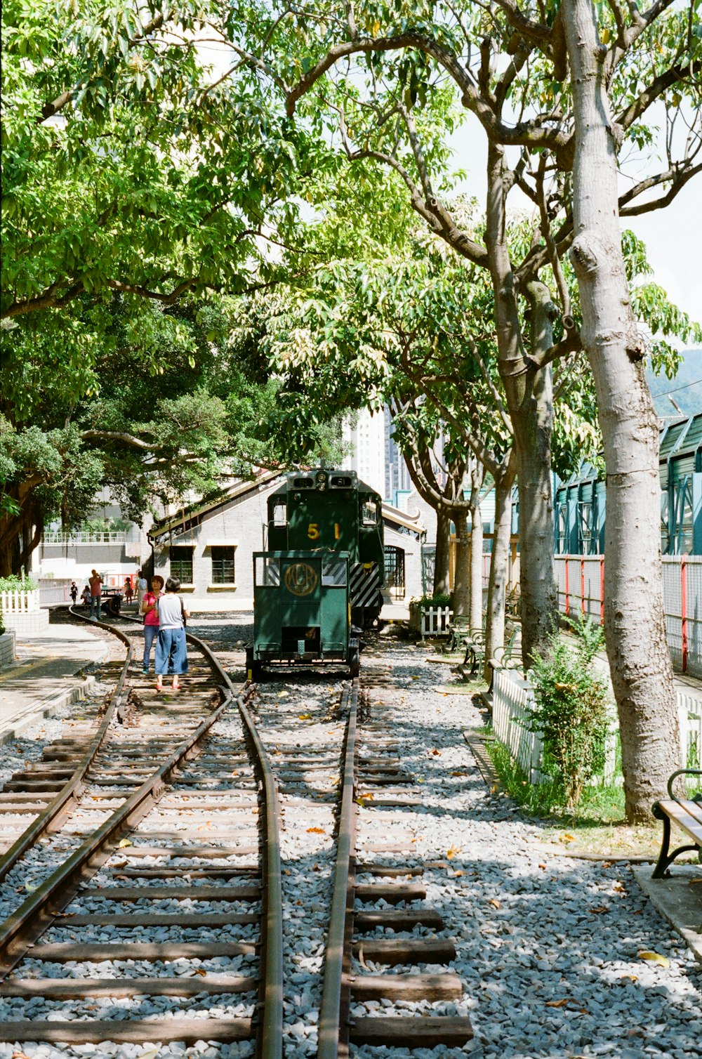 people walking on sidewalk near green train during daytime