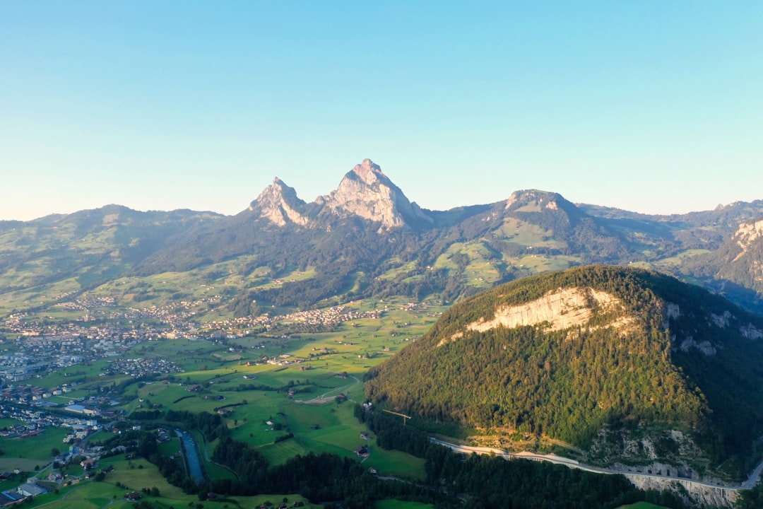 green grass field near mountain under blue sky during daytime