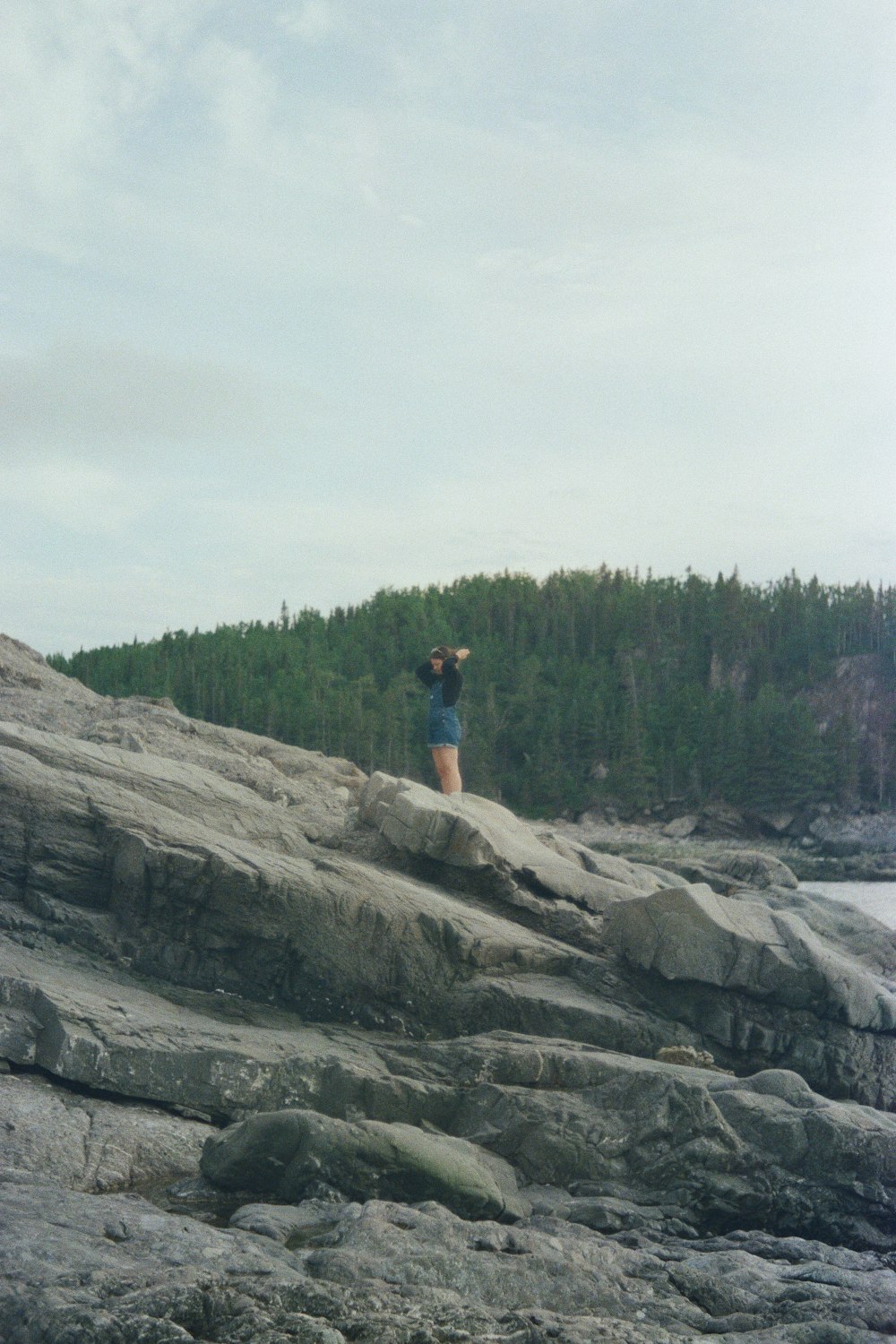 person in blue shirt and brown shorts standing on brown rock formation during daytime