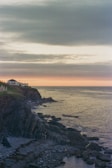 A scenic view of a coastal house with a sunset.