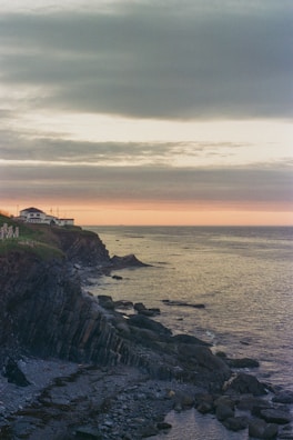 A scenic view of a coastal house with a sunset.