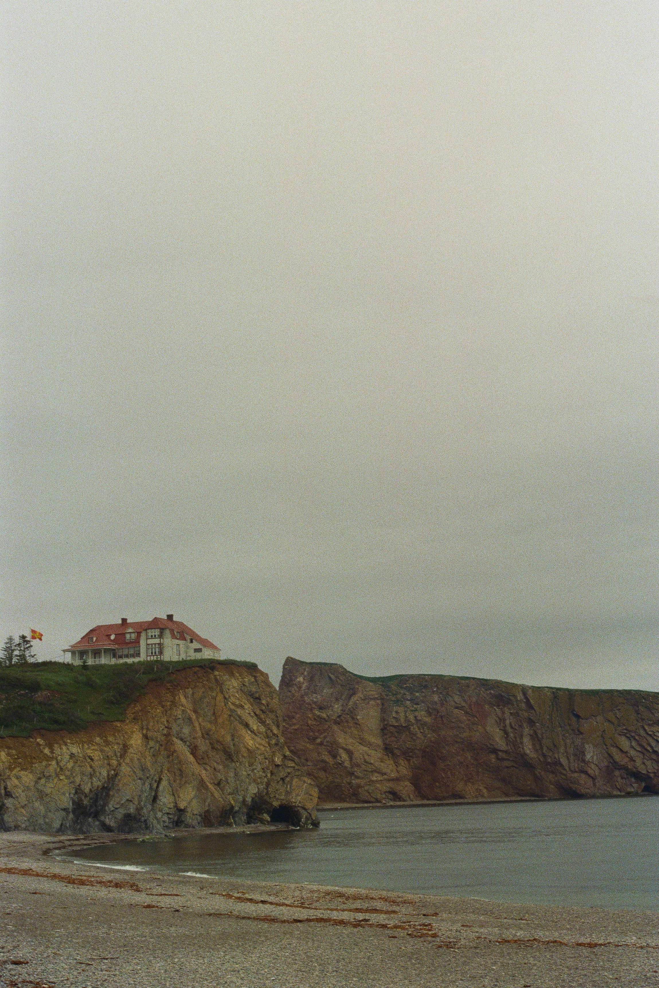 white and brown house on brown rock formation under white sky during daytime
