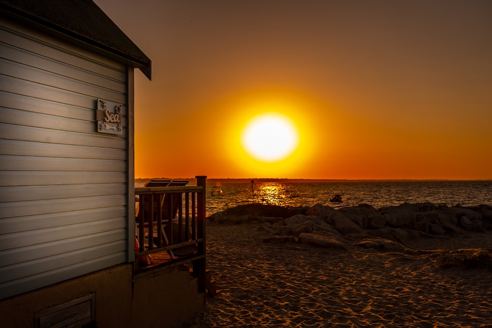 Maison en bois brun sur la plage au coucher du soleil
