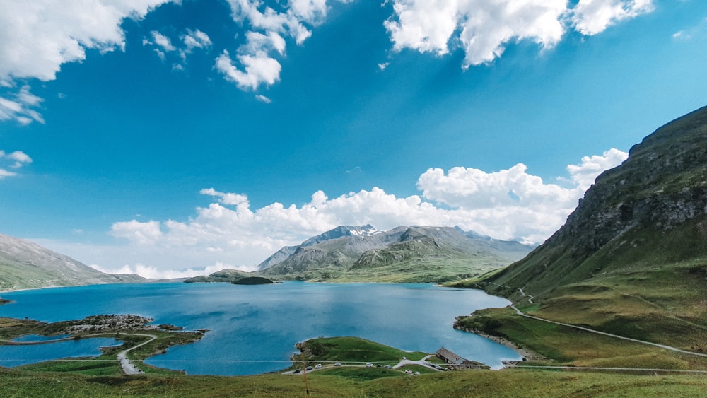 green and white mountains near body of water under blue sky during daytime